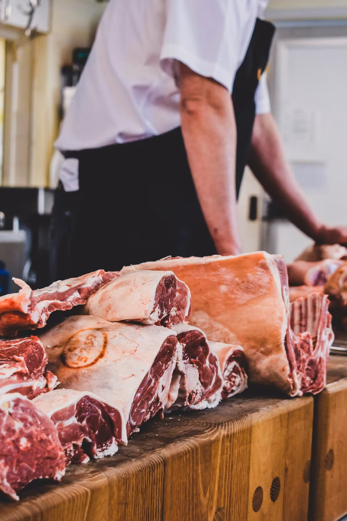 A butcher breaking down cuts on a wooden block